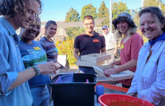 Volunteers cleaning and packing seed at an outdoor table
